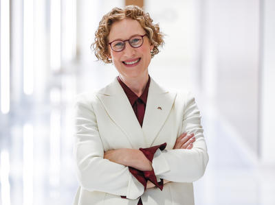 Dr. Rebecca Cunningham posing for a photo, wearing a white coat and glasses.