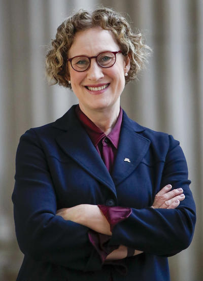 President Cunningham posing for a picture wearing a dark blue coat and glasses.